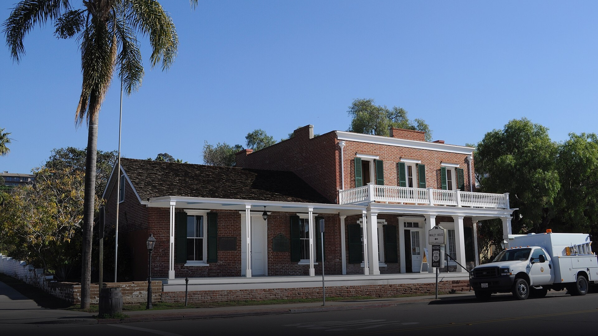 Front brick facade, white columns, and shuttered windows of the historic Whaley House museum in Old Town San Diego.