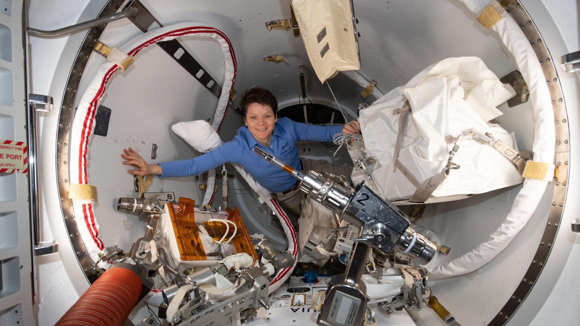 Astronaut inside the Quest Airlock after a spacewalk with space suit components
