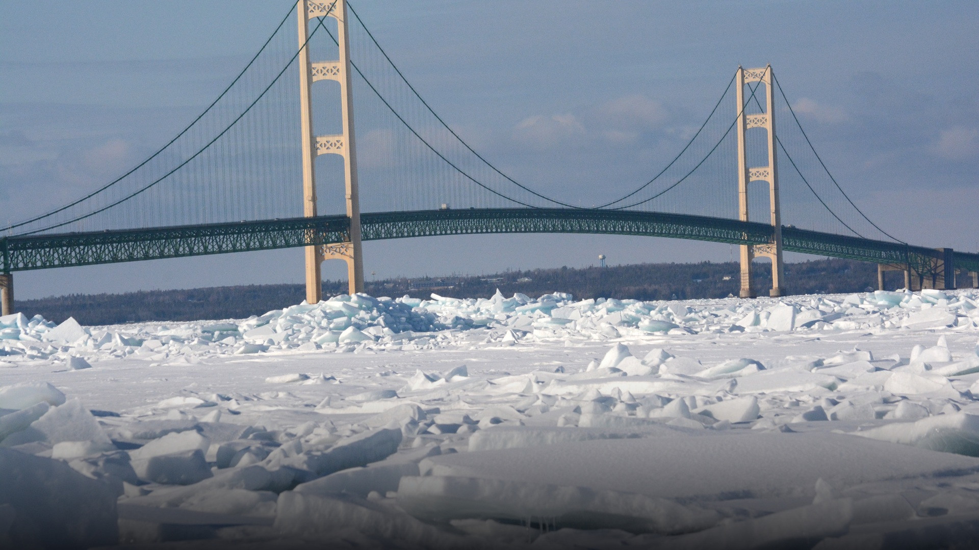 The Mackinac Bridge suspension towers stretching across an icy expanse of winter water and snow.