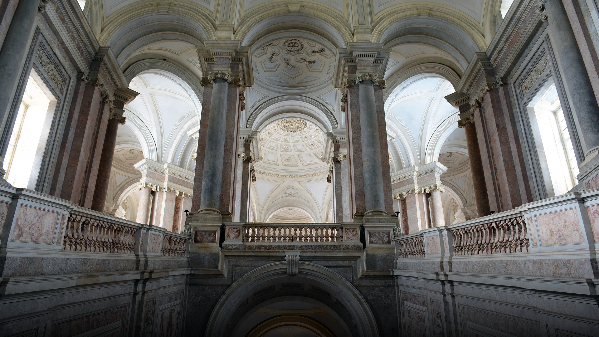 The monumental marble grand staircase and vaulted arches of the Royal Palace of Caserta in southern Italy.