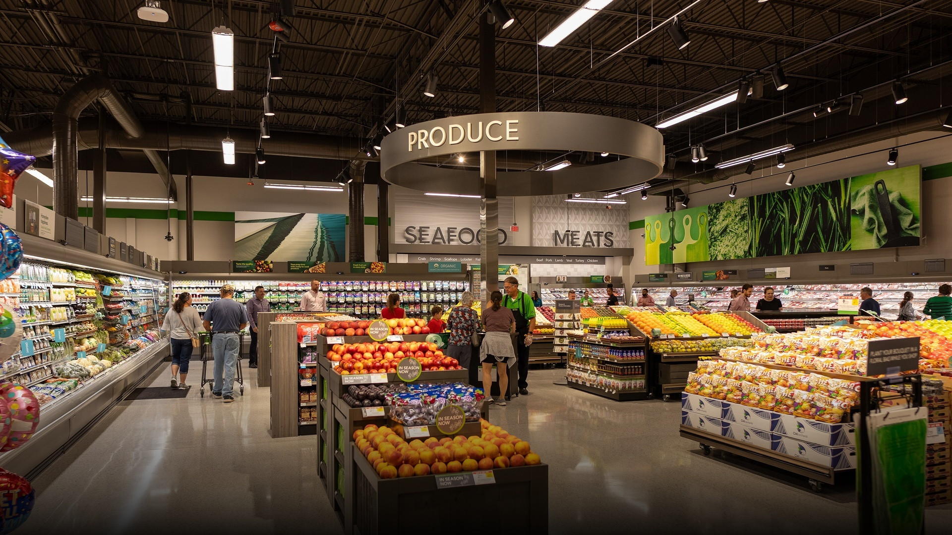 Produce, seafood, and meats department inside an American Publix supermarket with fresh fruit displays and refrigerated grocery cases.