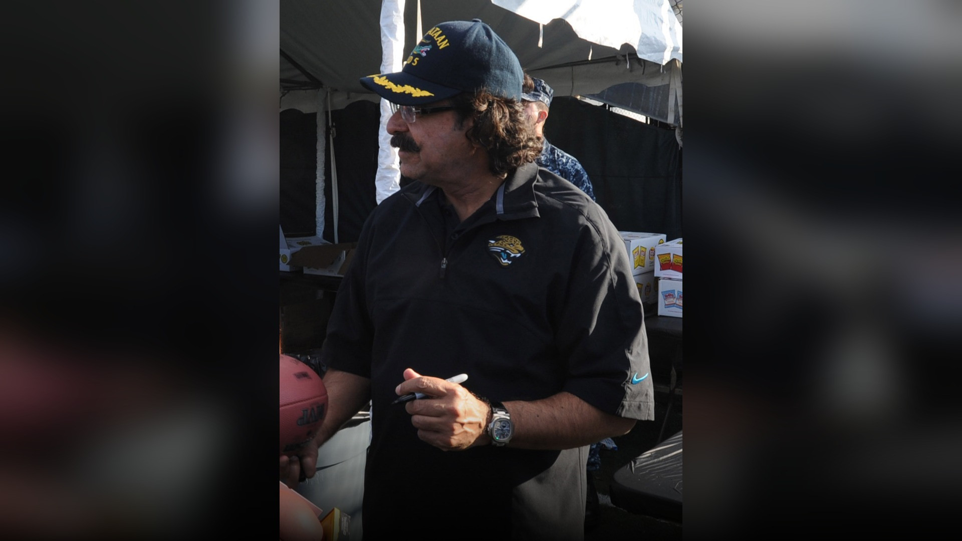 Shahid Khan smiling on an NFL football sideline.