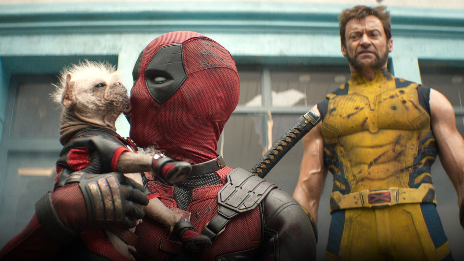 Ryan Reynolds as Deadpool holding Dogpool in tactical red suit with dual swords.