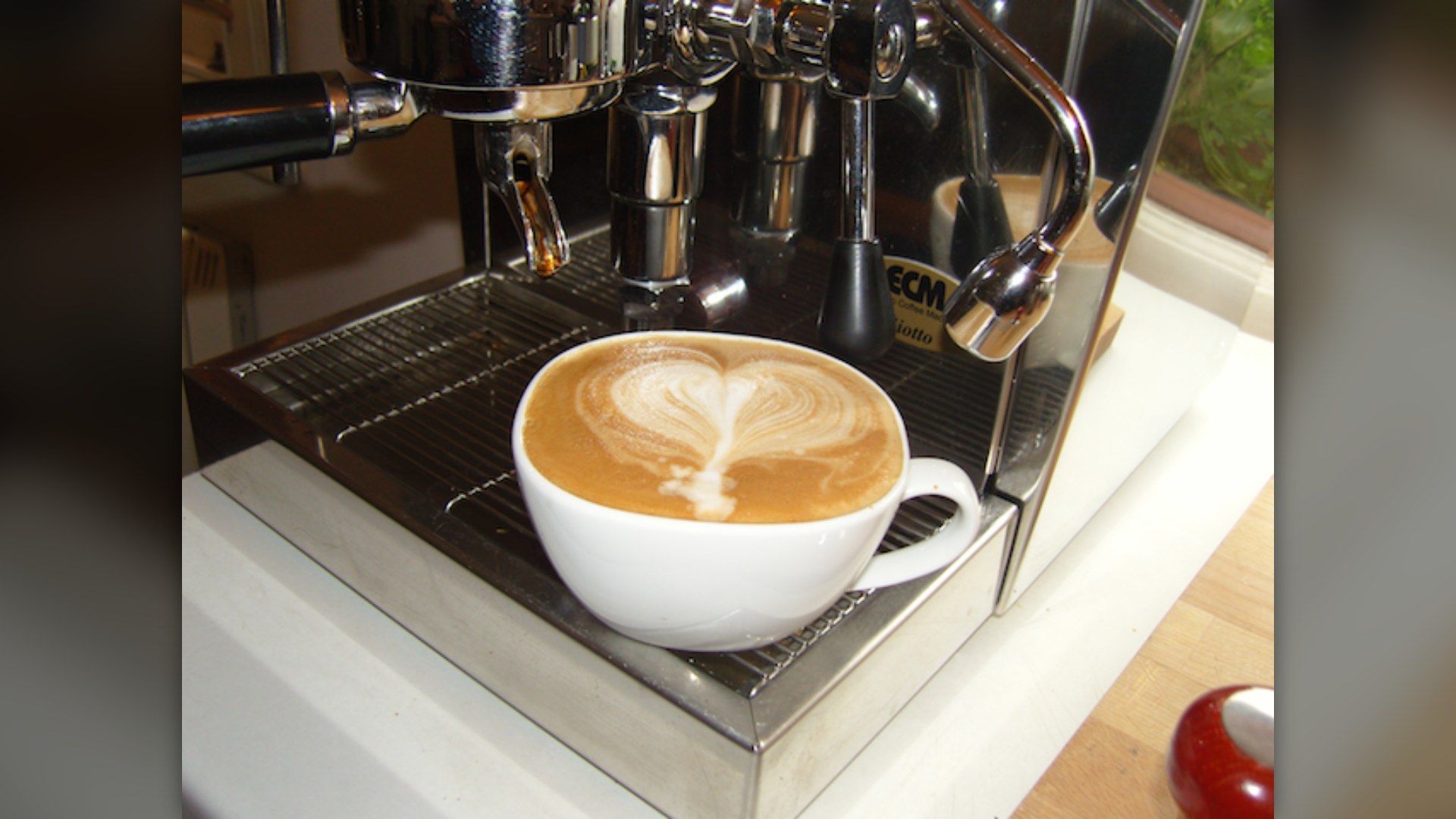 A white cup of flat white coffee with smooth velvety microfoam latte art on top