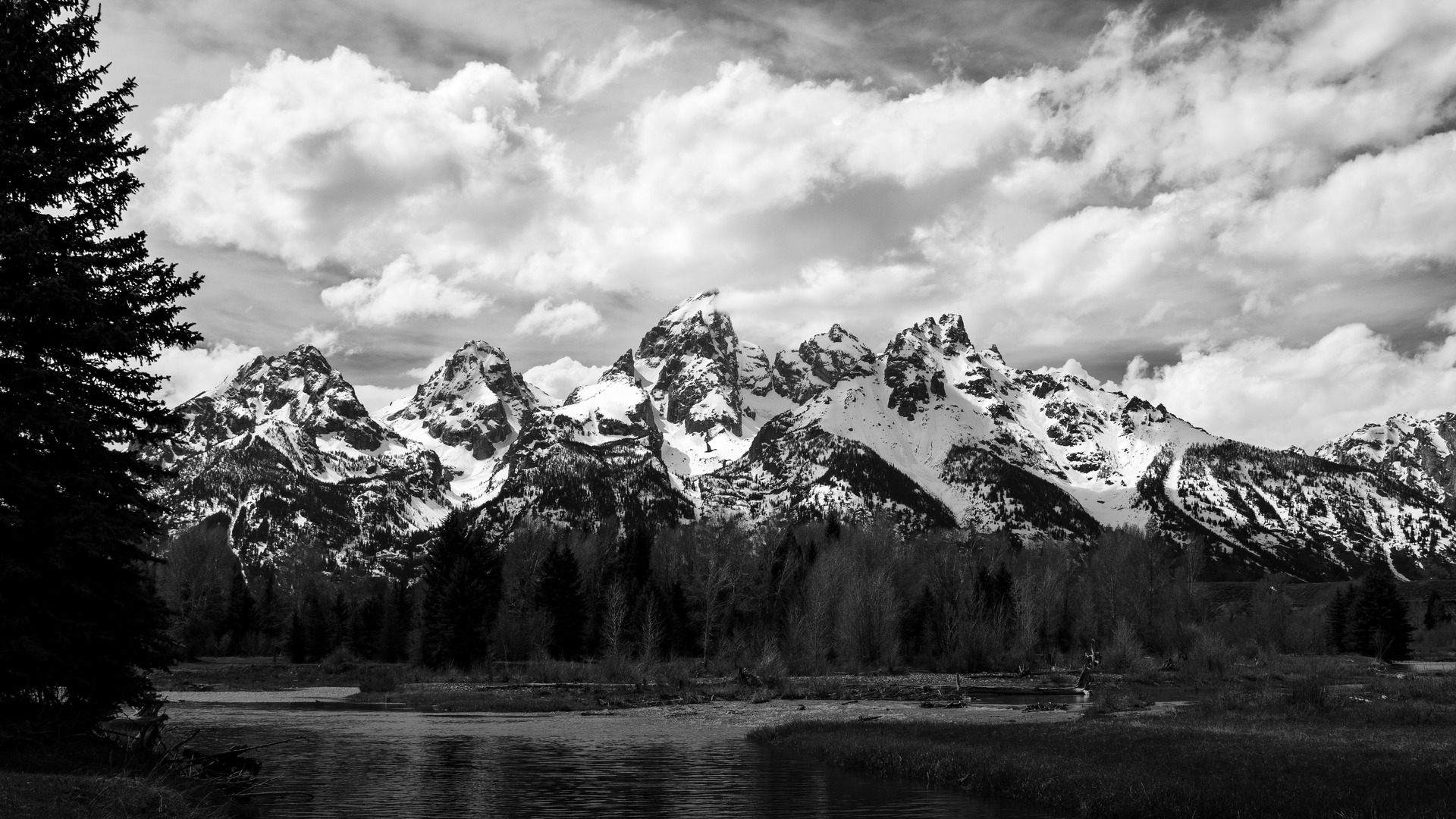The dramatic jagged peaks of the Teton Range reflected in the calm waters of the Snake River at Schwabacher Landing in Grand Teton National Park, Wyoming.