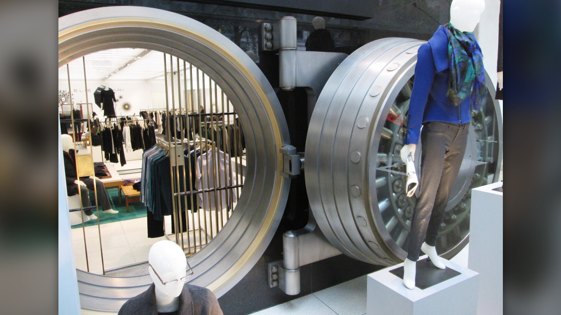 Massive circular steel bank vault door with exposed locking gears and bolts.