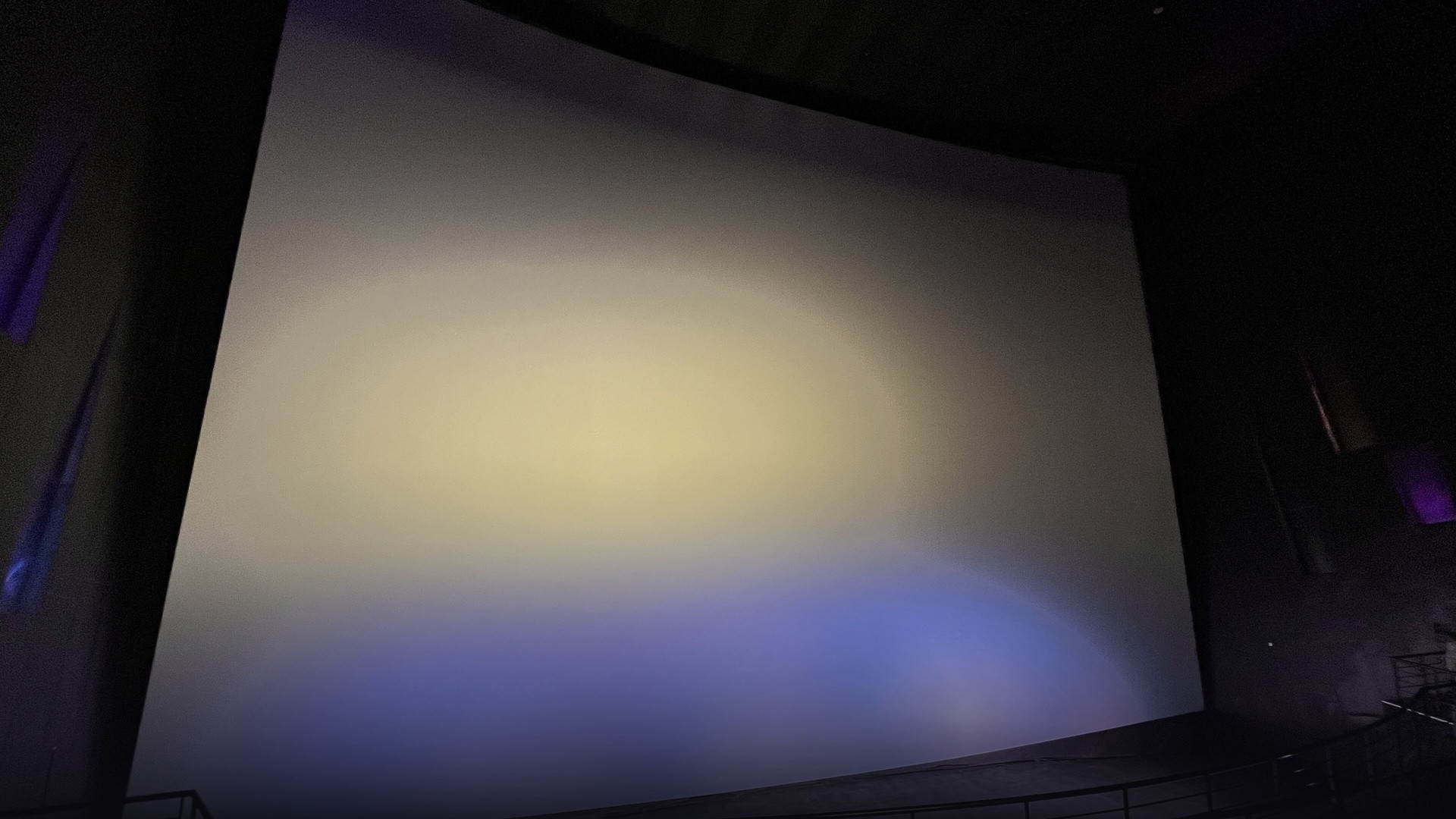 Grand illuminated IMAX cinema theatre auditorium screen demonstrating expanded theatrical scale.