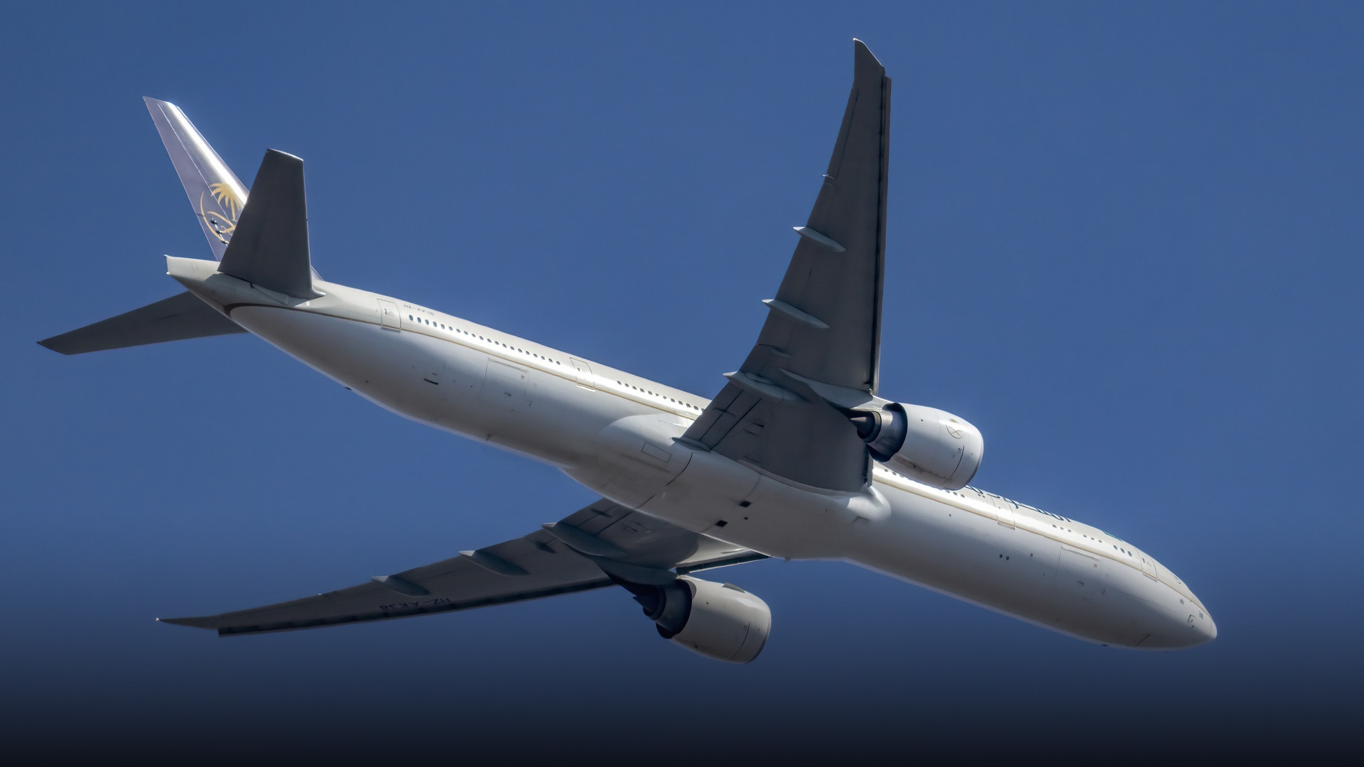 A Saudia Boeing 777-300ER climbing into the blue sky shortly after departure.