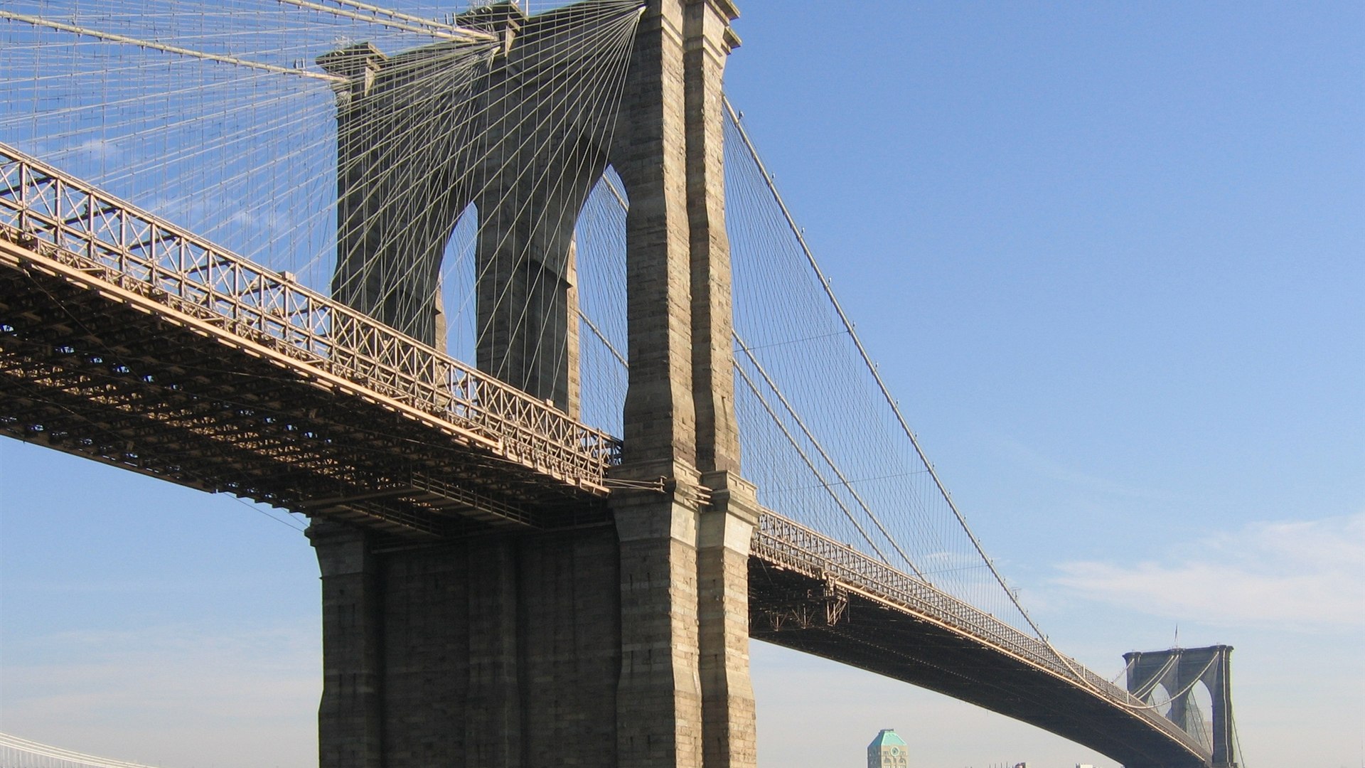 Brooklyn Bridge stone towers and steel cables spanning the East River at dusk