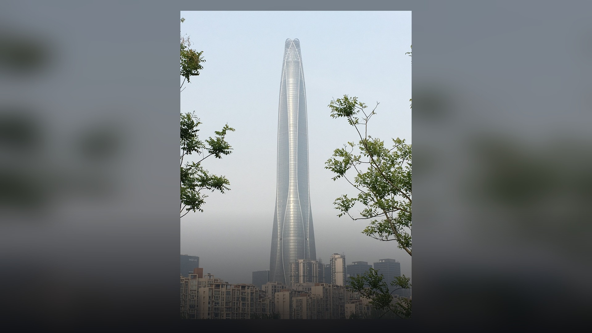 The curved glass facade of the Tianjin CTF Finance Centre rising into the sky.
