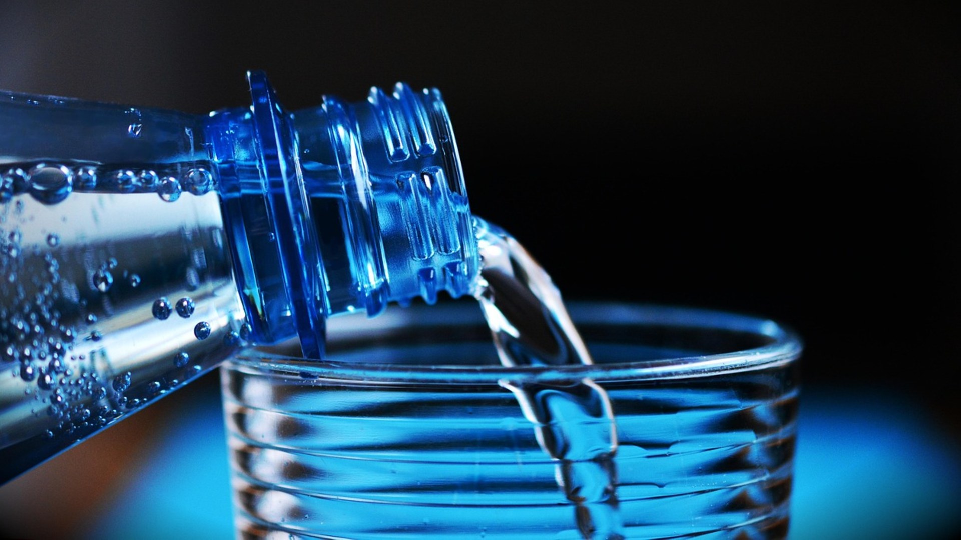 Mineral water being poured from a bottle into a drinking glass for daily hydration