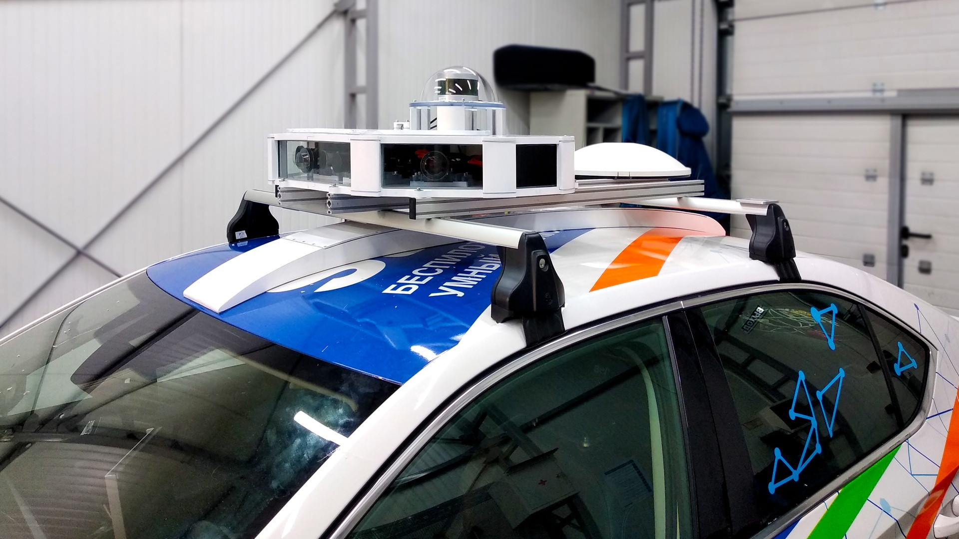 Autonomous white passenger car equipped with rooftop 3D LiDAR and optical camera sensors.