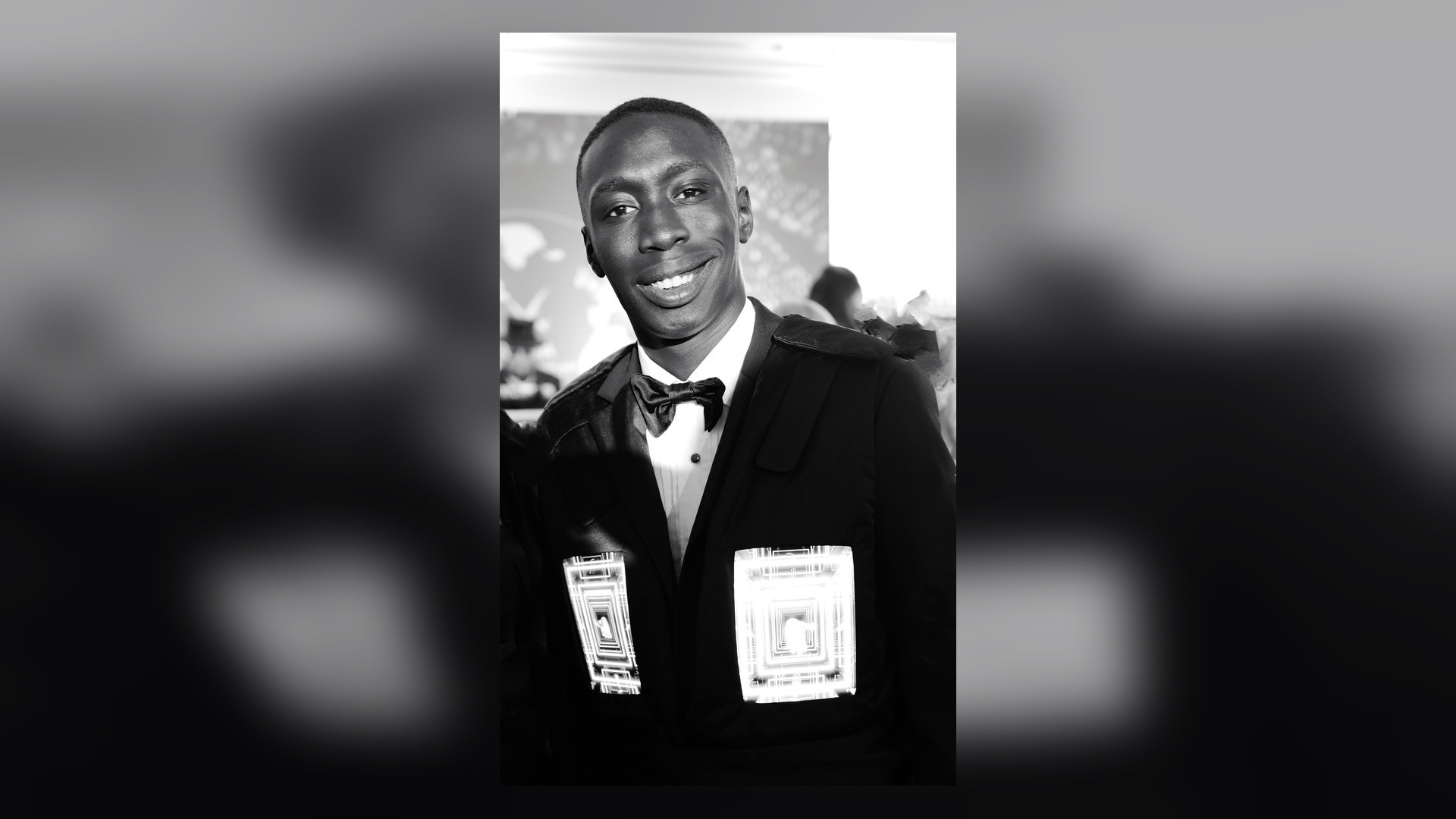 Portrait of Khaby Lame in a black tuxedo smiling at a gala event.