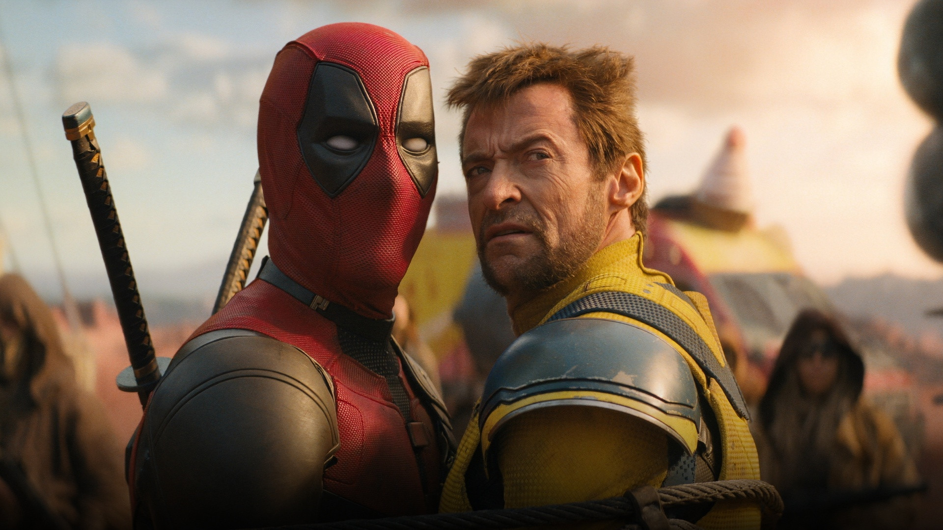 Hugh Jackman as Wolverine in yellow suit with adamantium claws beside Deadpool.