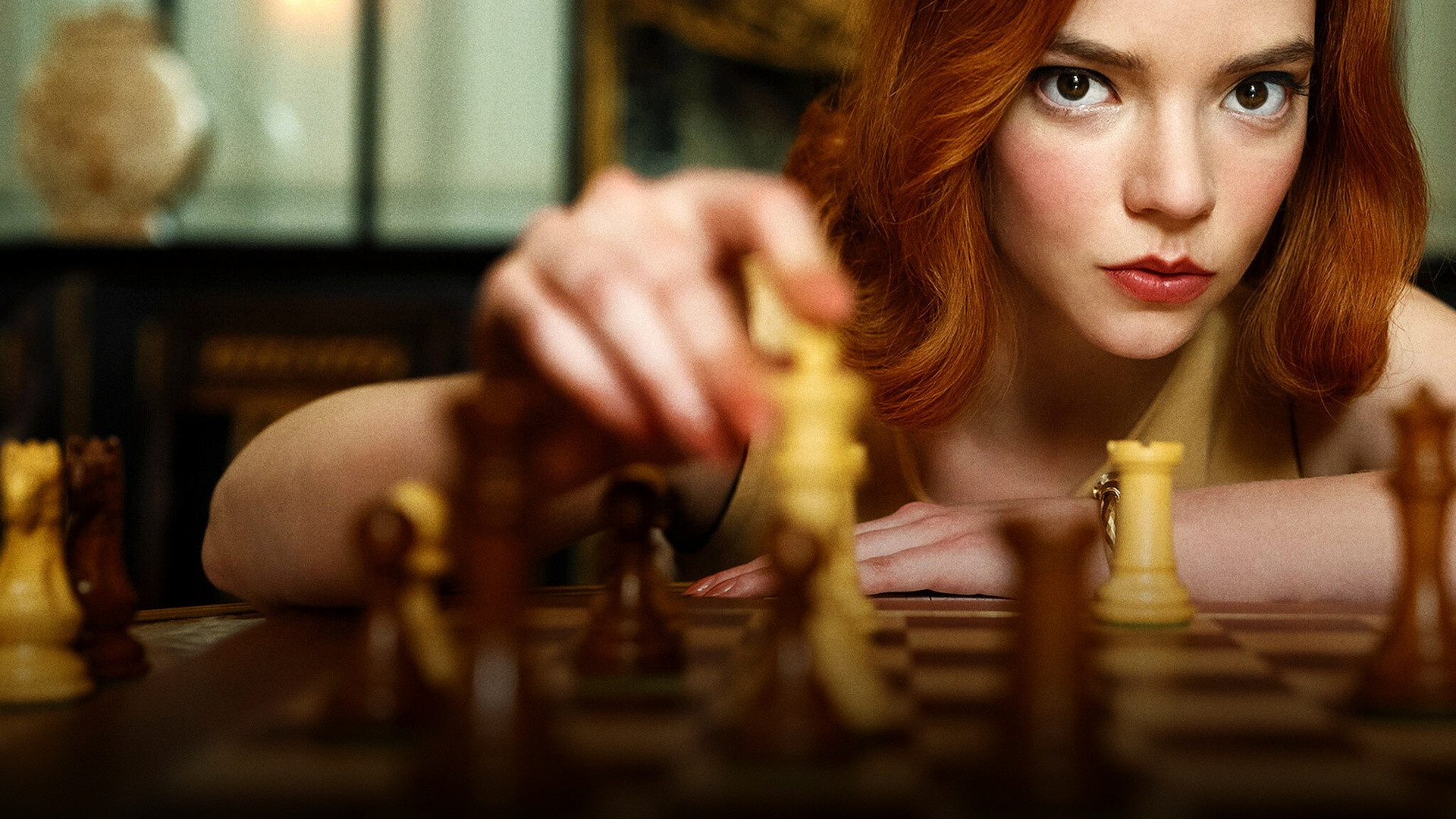Anya Taylor-Joy as Beth Harmon leaning over a chessboard in The Queen's Gambit