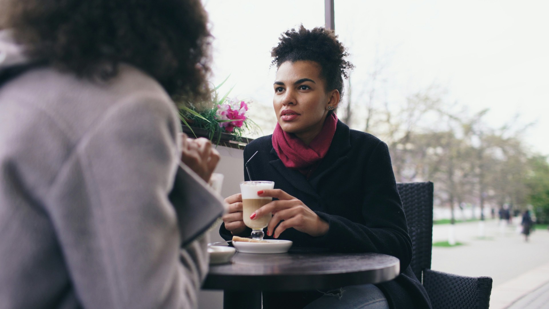 Two women talking at an outdoor cafe table during an intense discussion