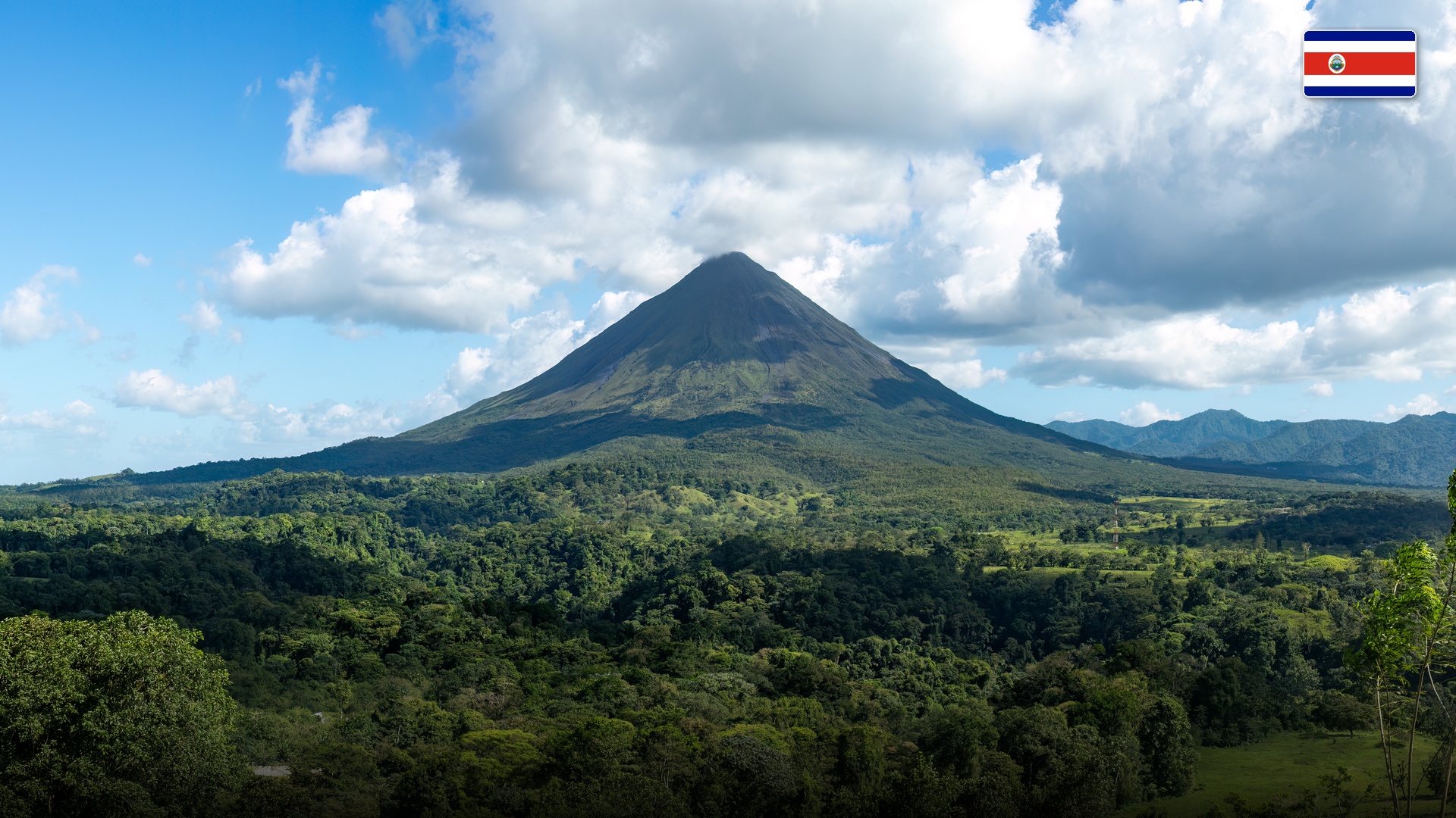 Symmetrical Arenal Volcano rising over lush tropical rainforest canopy in La Fortuna.