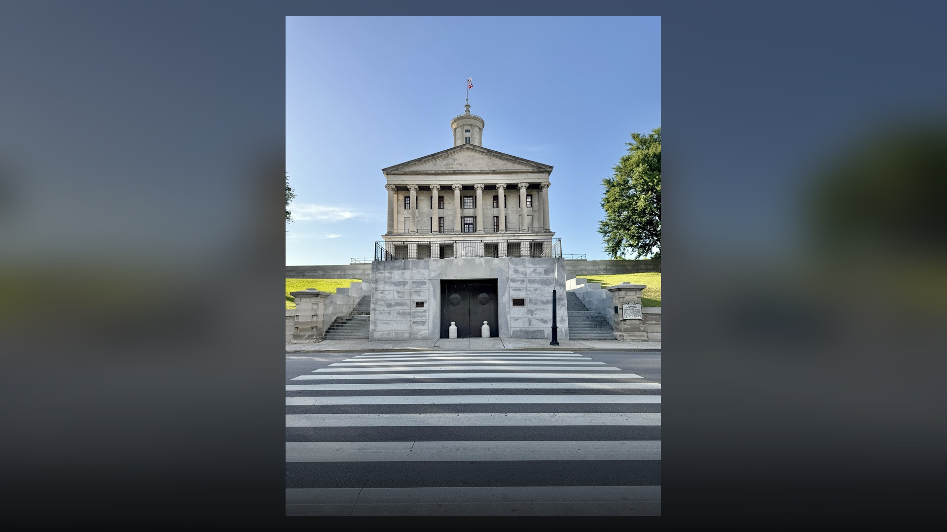 The Tennessee State Capitol building and cupola tower in Nashville viewed across a pedestrian walkway.