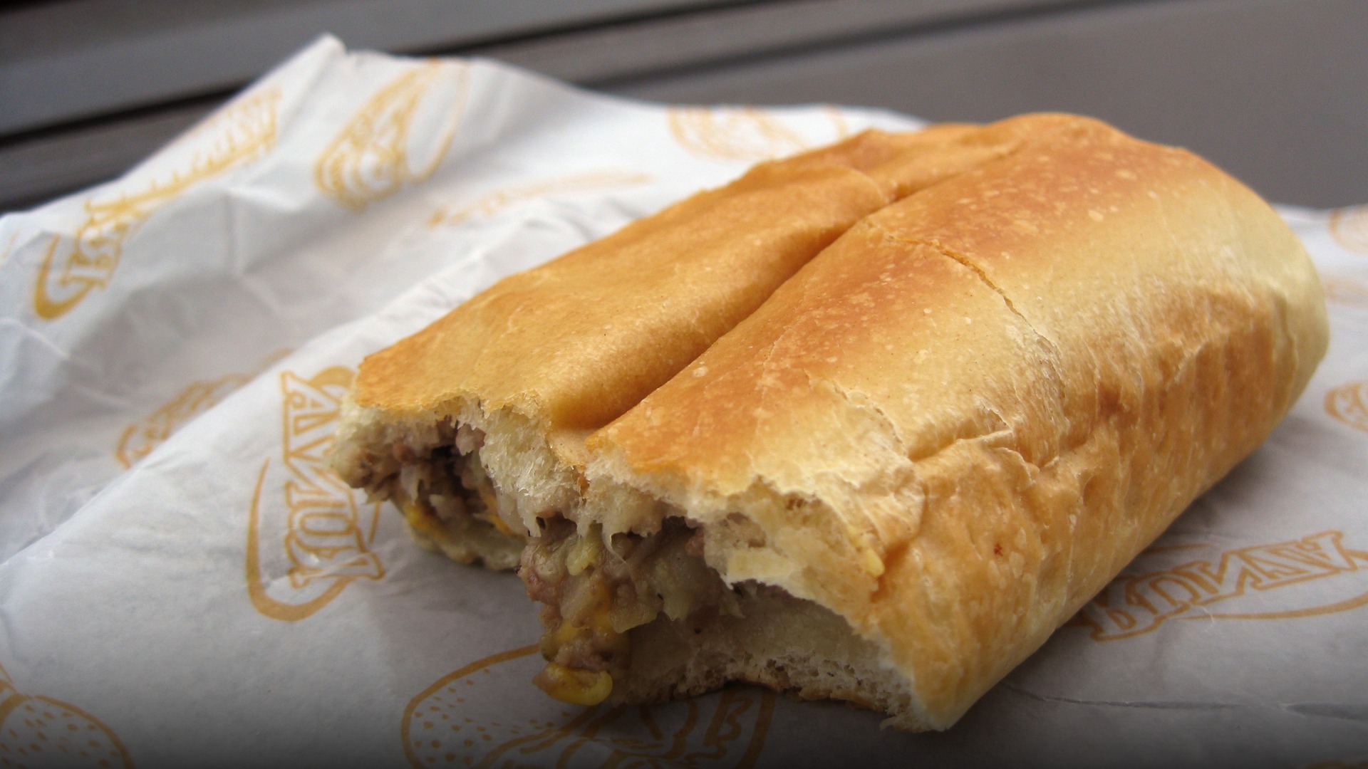 A freshly baked yeast bread Runza sandwich cut open revealing seasoned ground beef, onion, and cabbage filling.