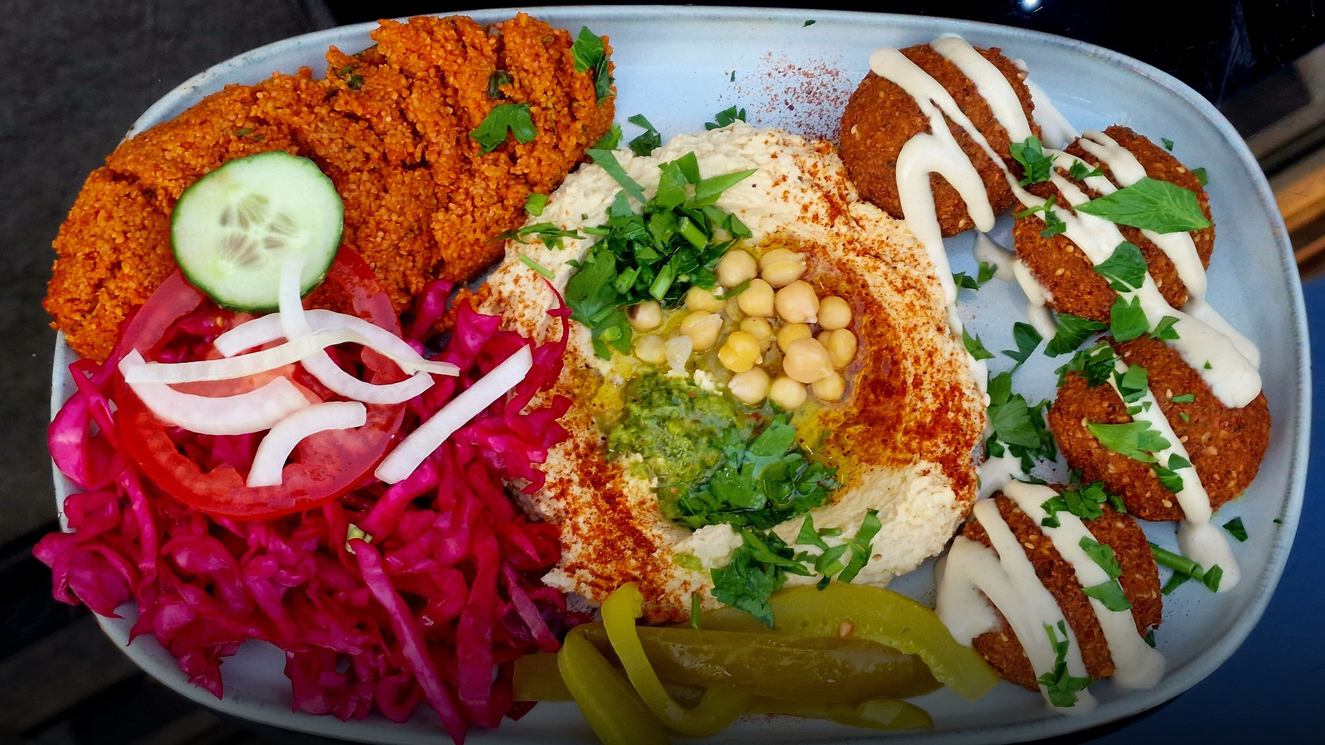 Freshly fried golden-brown falafel patties served on a colorful plate with fresh salad, tahini, and pita.