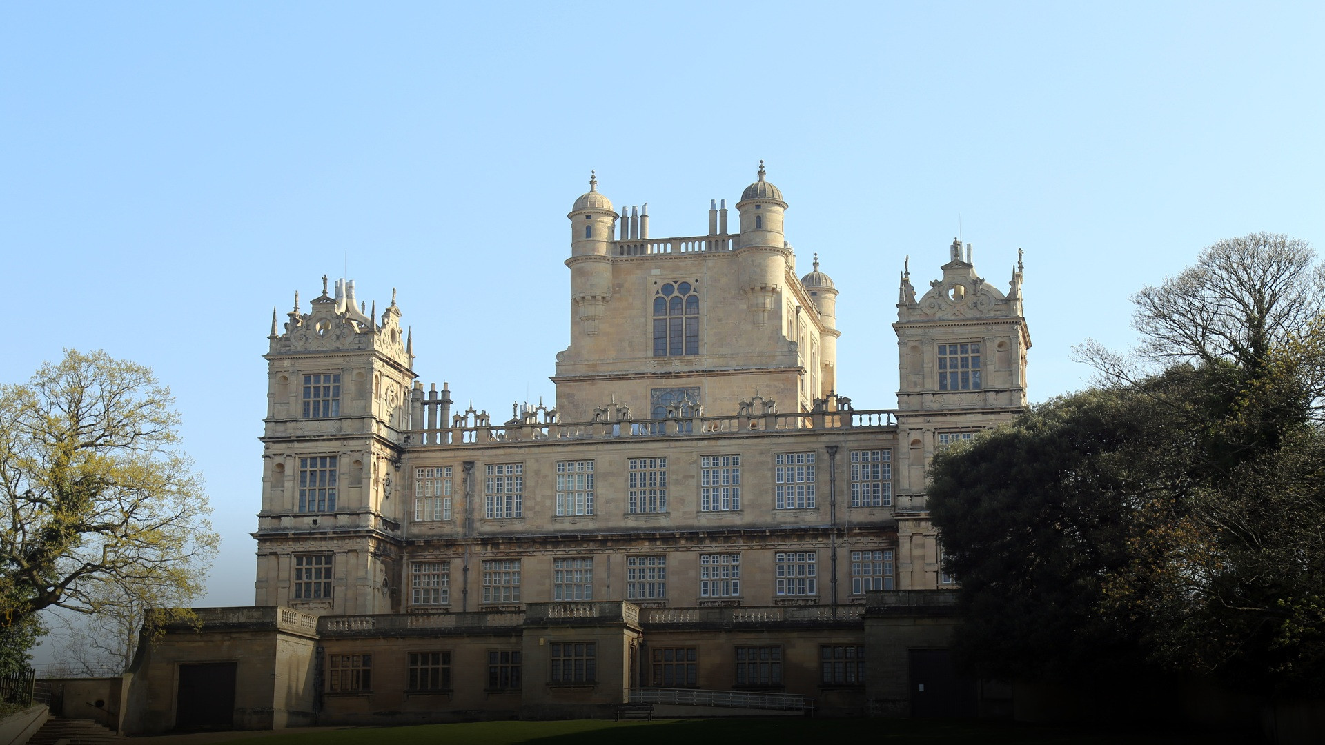 The grand stone towers and mullioned windows of Elizabethan Wollaton Hall set against manicured parkland.
