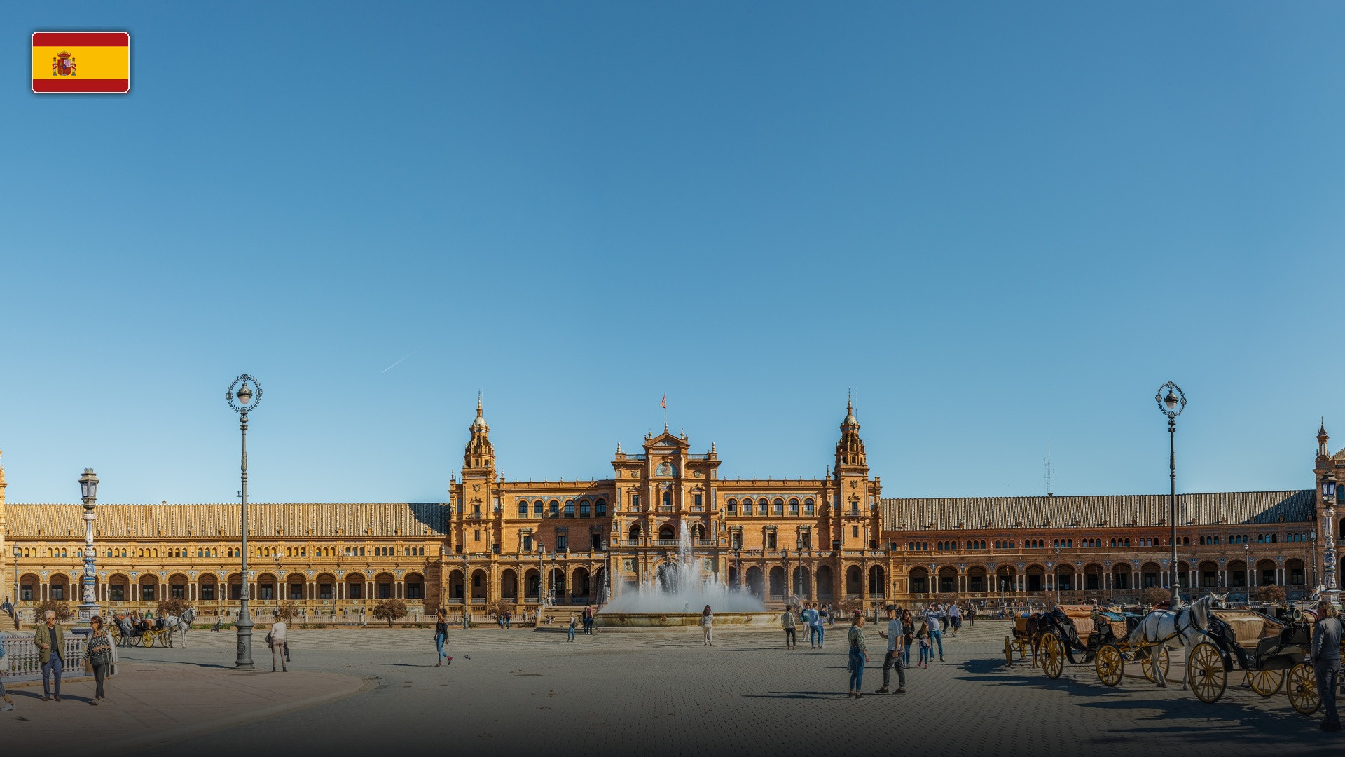 The grand Renaissance and neo-Moorish palace, towers, and fountain of Plaza de España in Seville, with the flag of Spain.