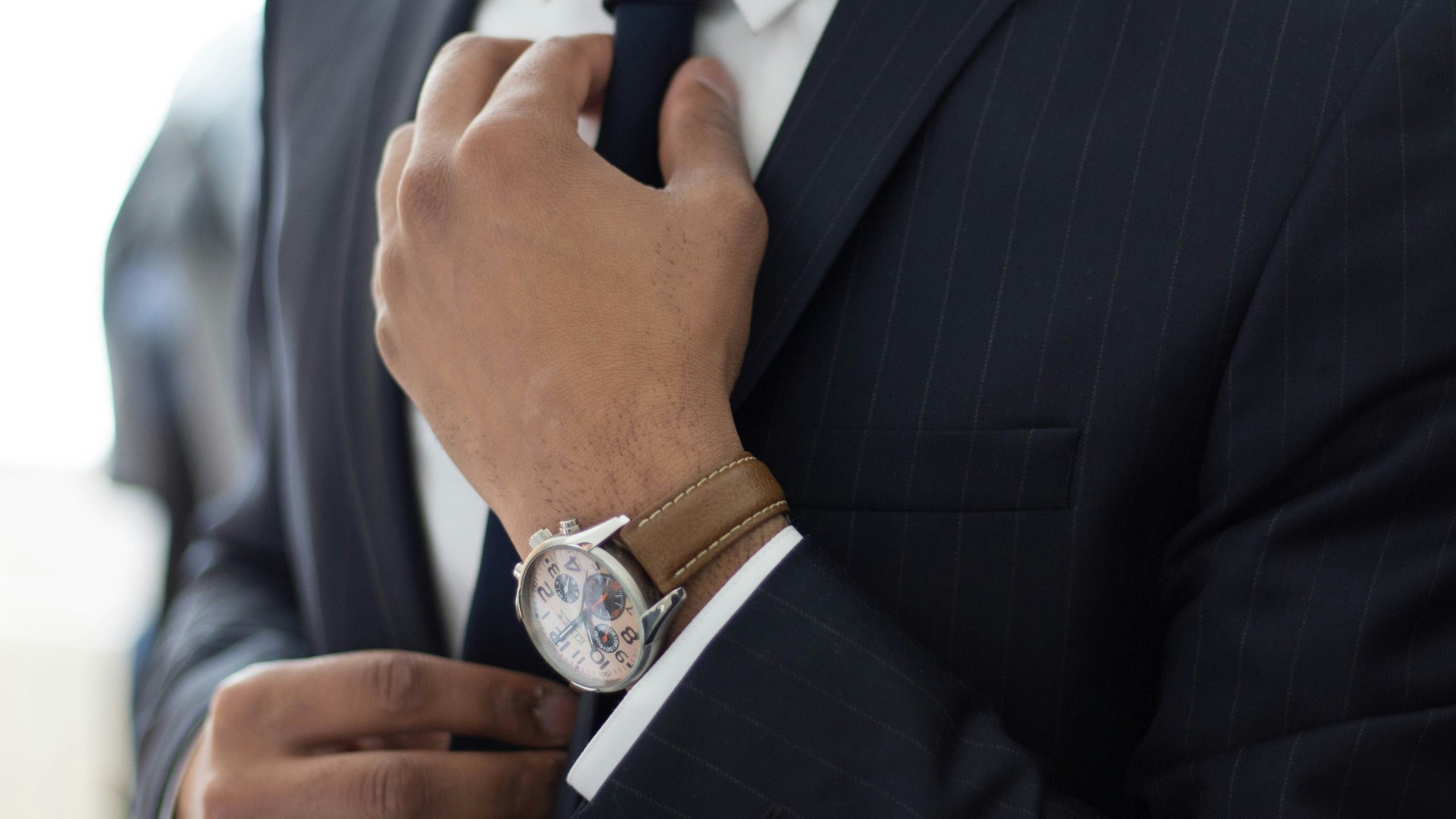 Man in a black suit showing off his luxury watch