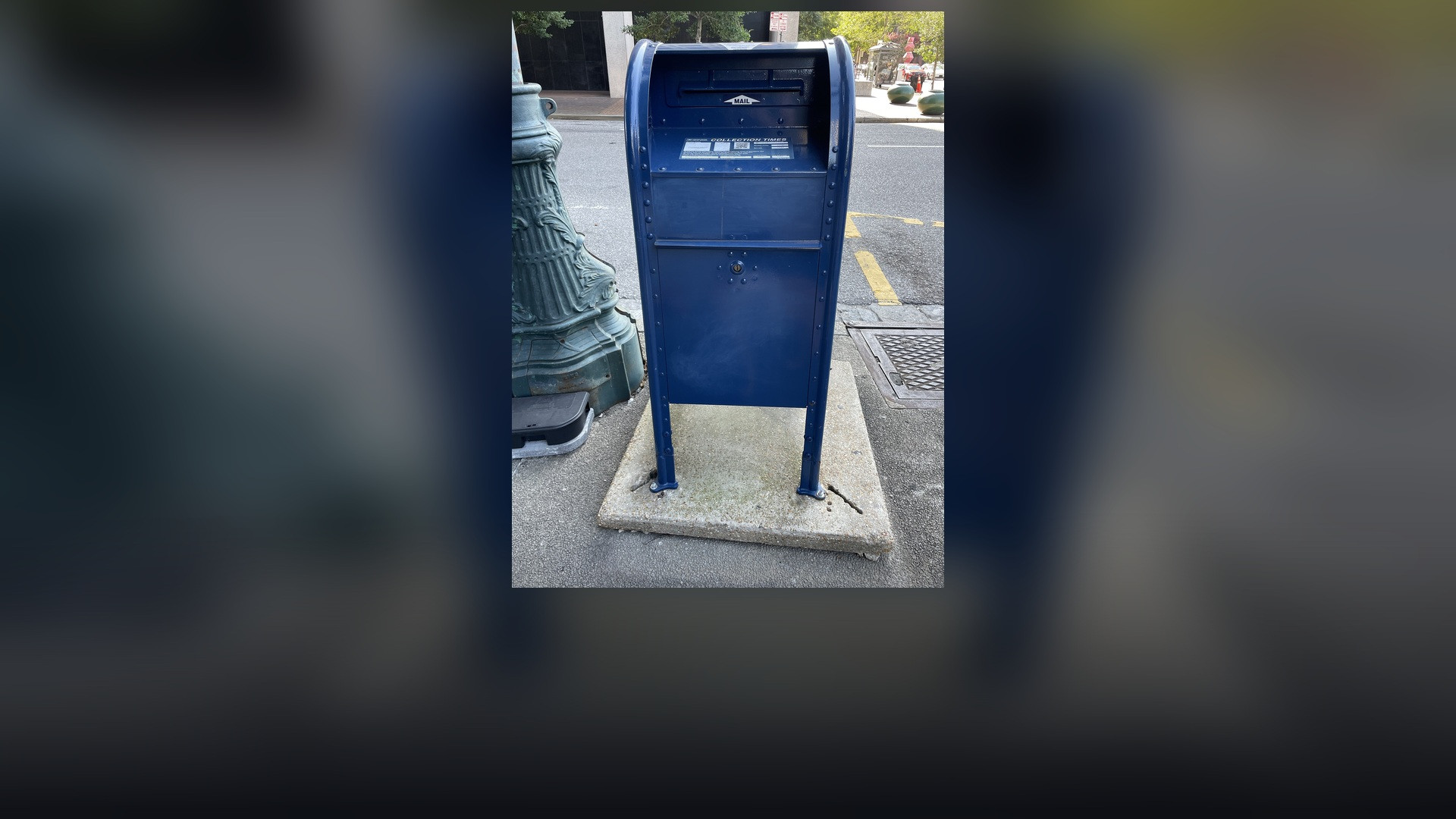 Iconic blue United States Postal Service collection drop box on an American street.