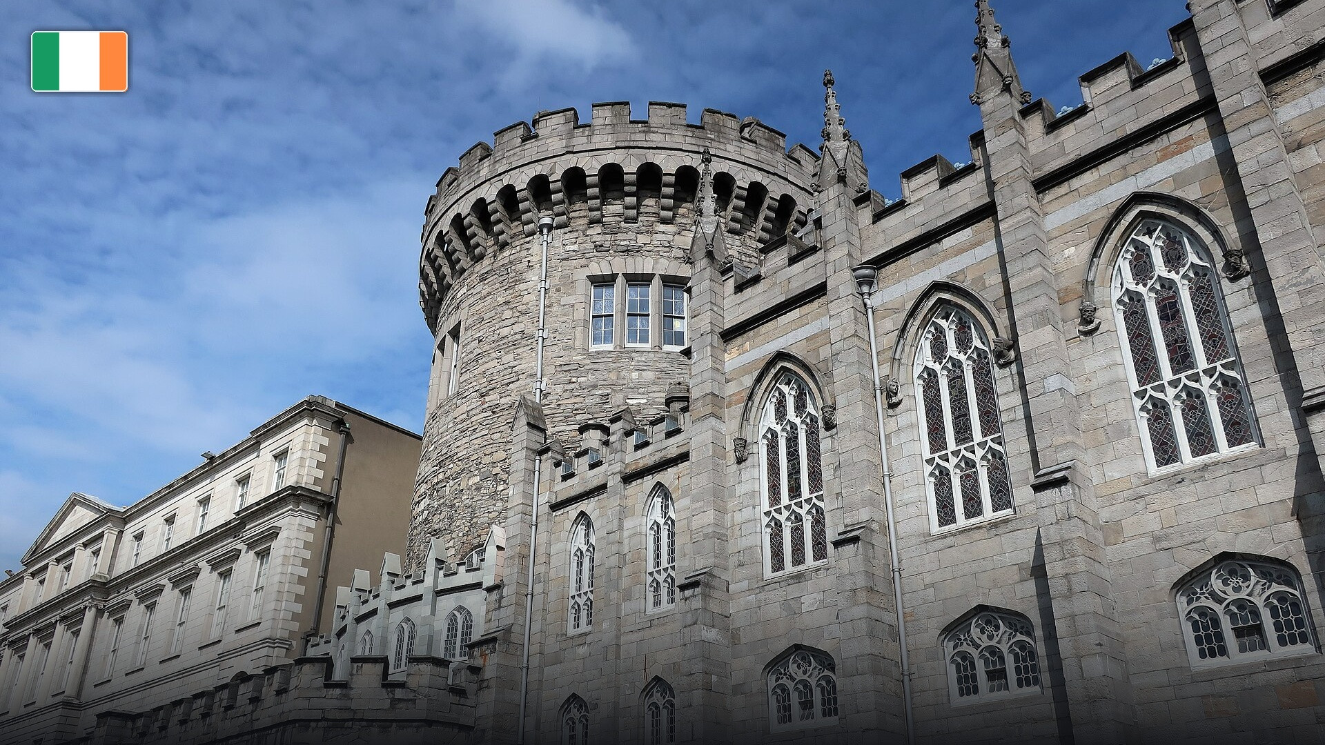 The historic stone Record Tower and flower gardens of Dublin Castle, with the flag of Ireland.