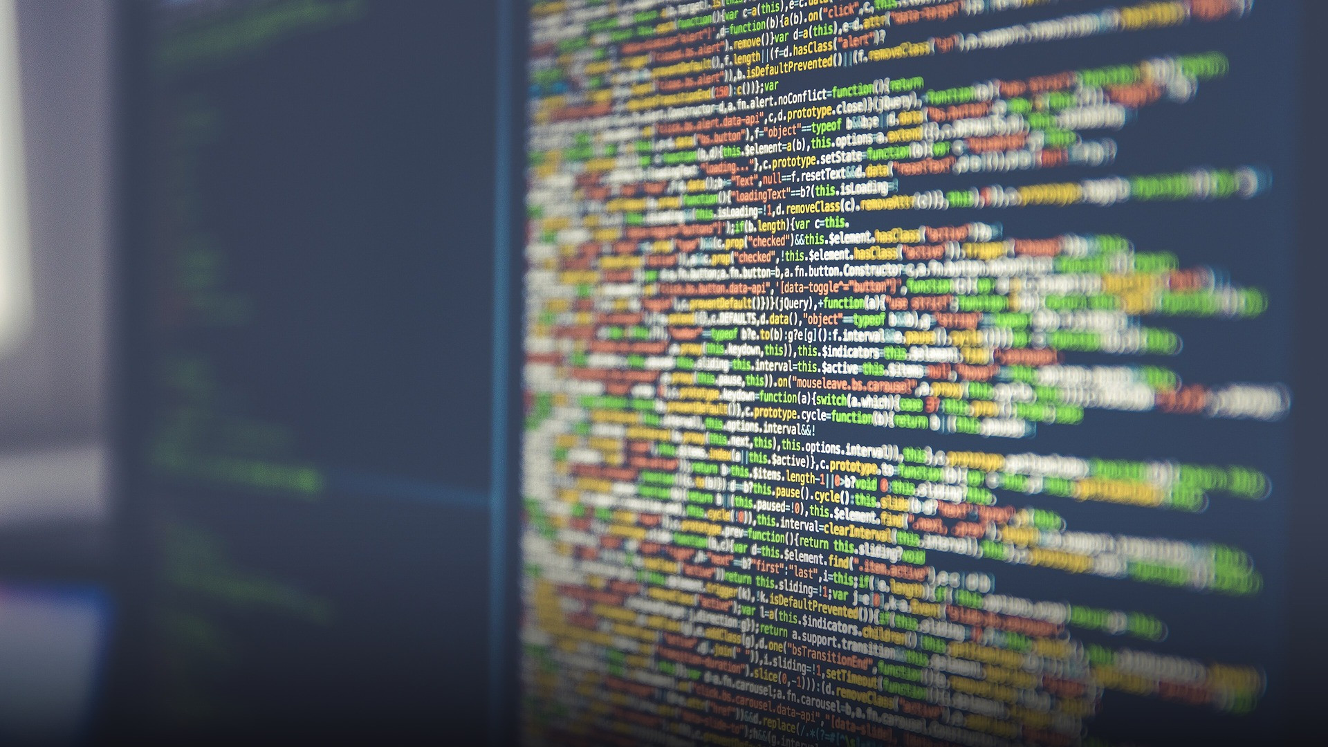 Computer screen displaying colored lines of software code and digital programming syntax.