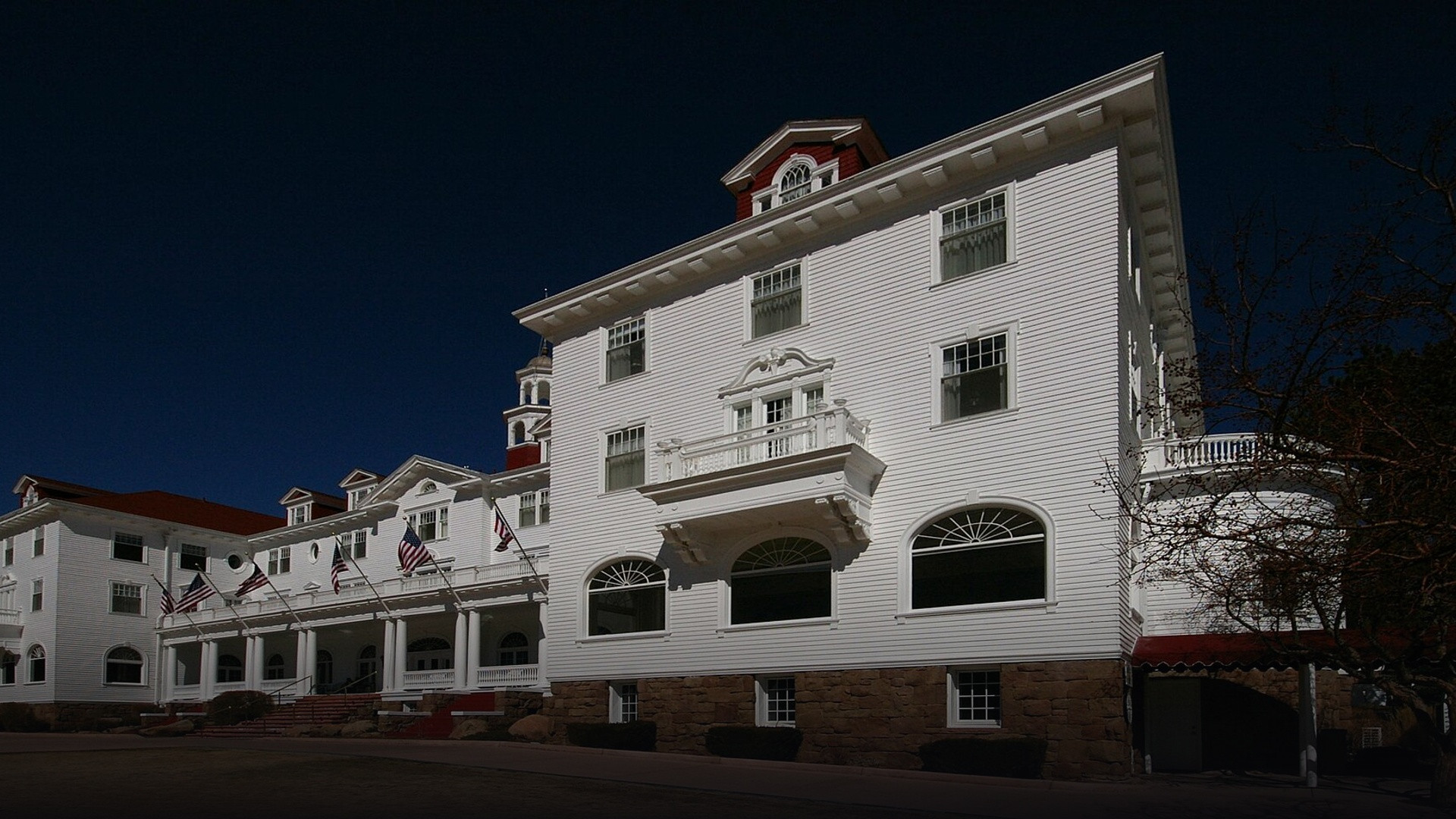Grand neoclassical white facade and red gabled roofs of The Stanley Hotel set against the Colorado Rocky Mountains in Estes Park.