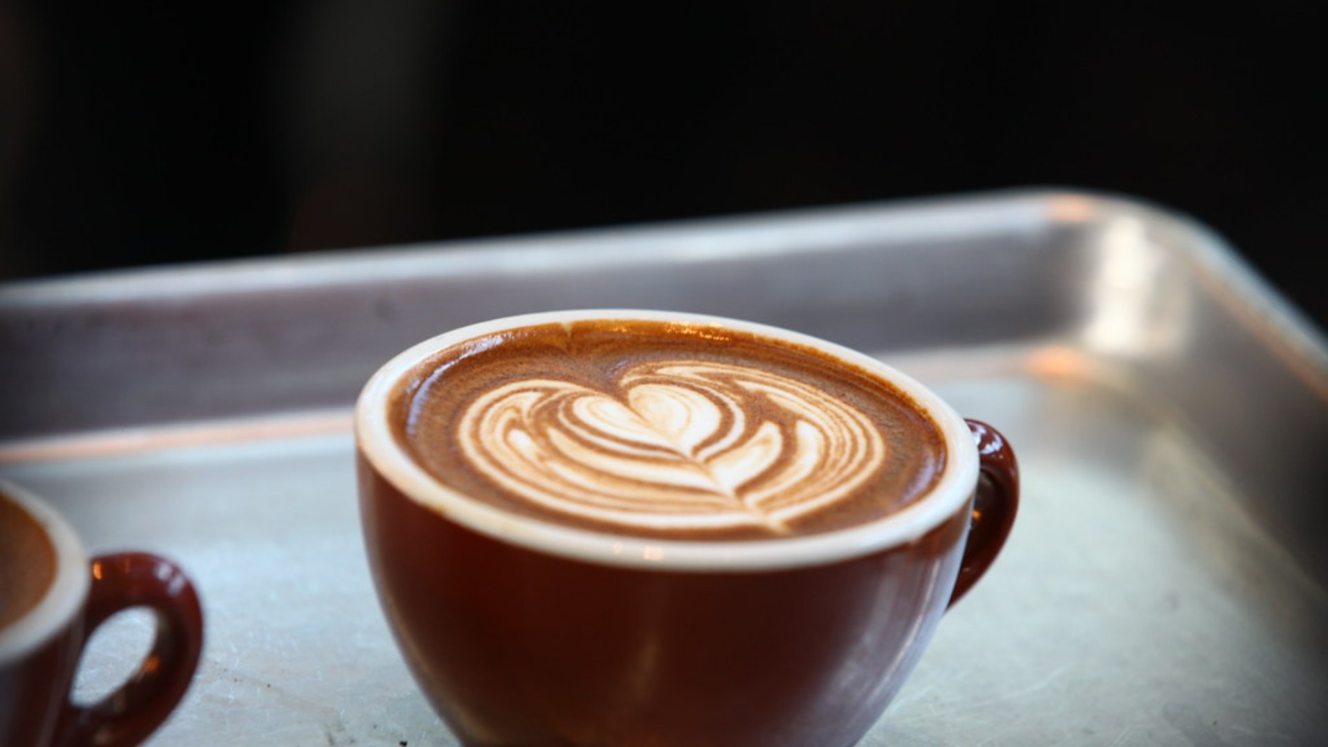 Barista pouring intricate latte art into a coffee cup at the Latte Art World Championship in Seattle