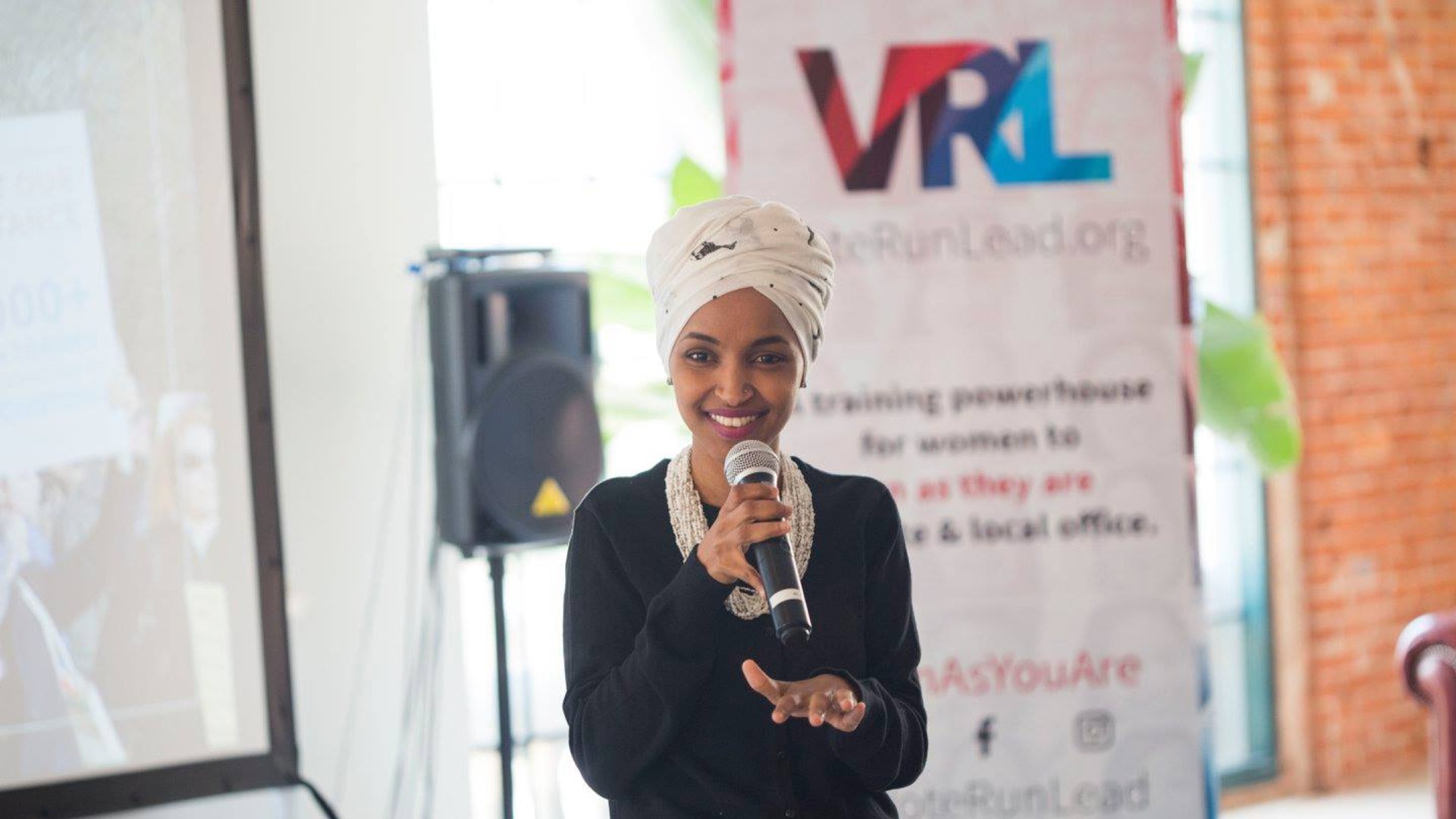Ilhan Omar speaking into a microphone at a forum