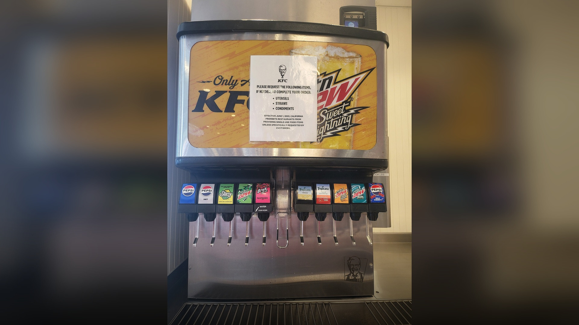 A self-serve soda fountain dispenser in a fast food dining area.