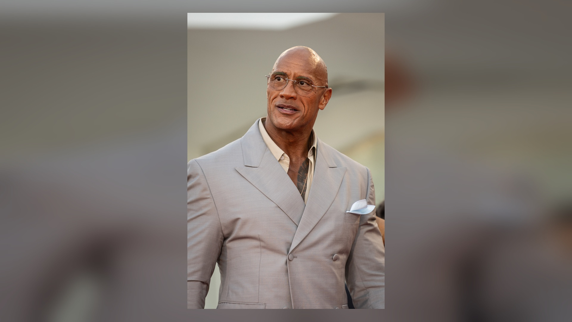 Portrait of Dwayne The Rock Johnson in a tailored suit at a red carpet premiere.