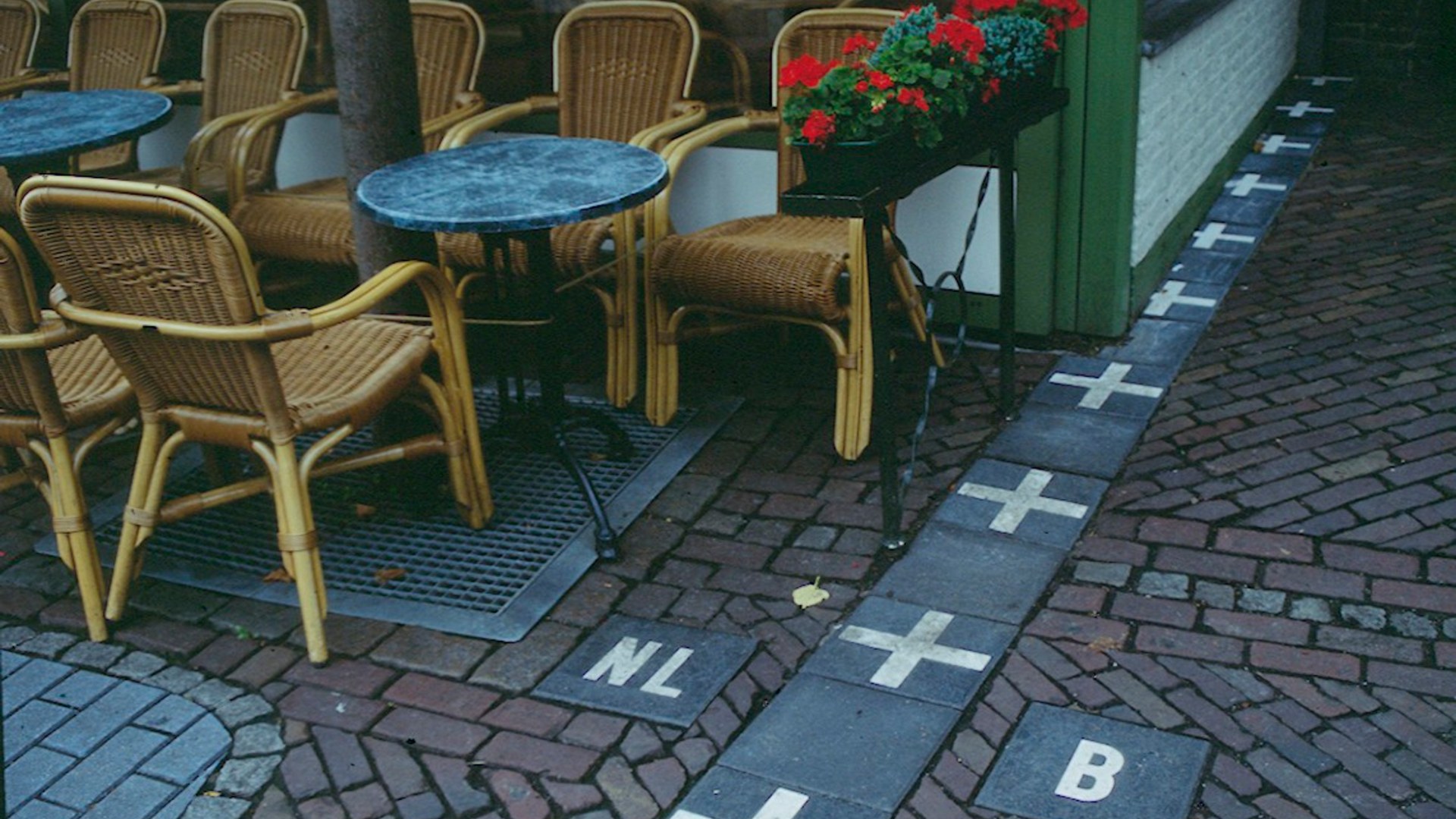 Landscape street photograph in Baarle showing white pavement crosses marking the border between Baarle-Nassau (Netherlands) and Baarle-Hertog (Belgium).