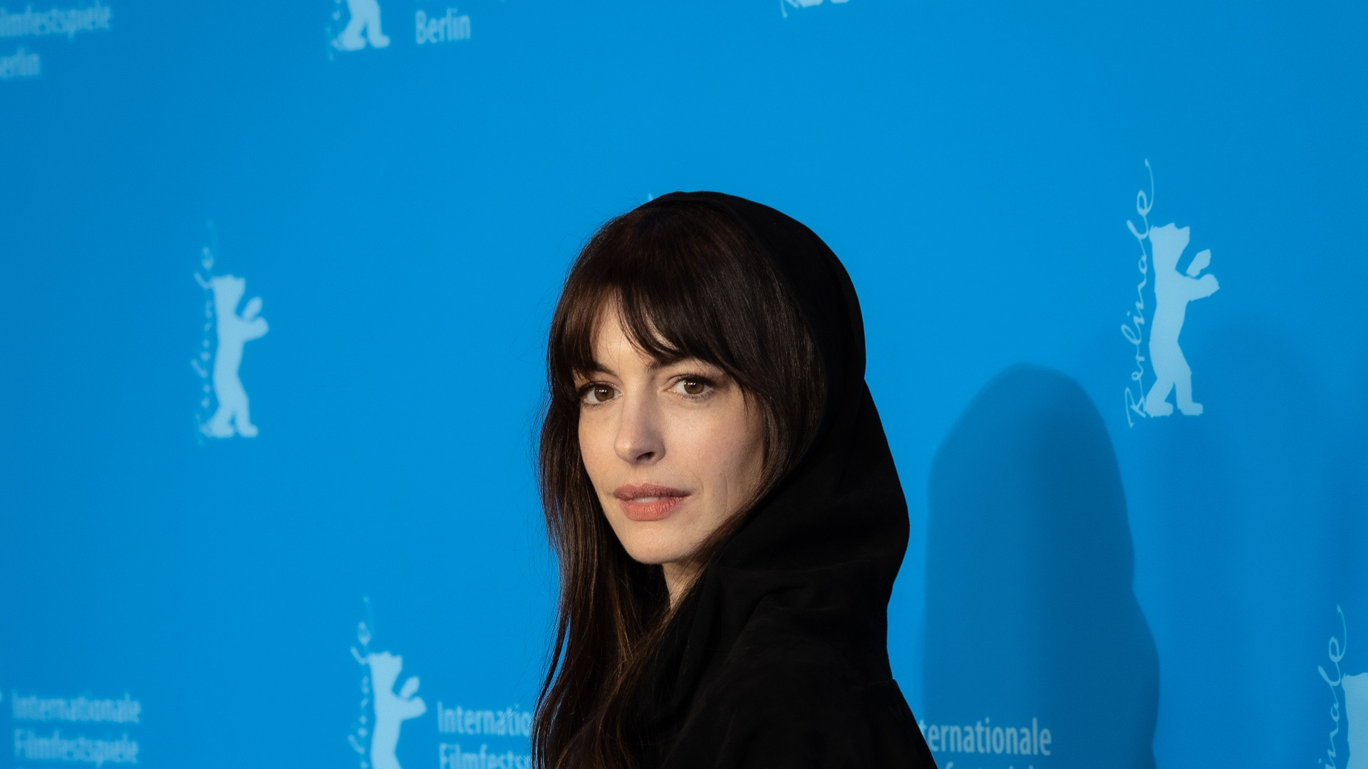 Portrait photograph of Anne Hathaway looking intently to the side with elegant swept-back dark hair.