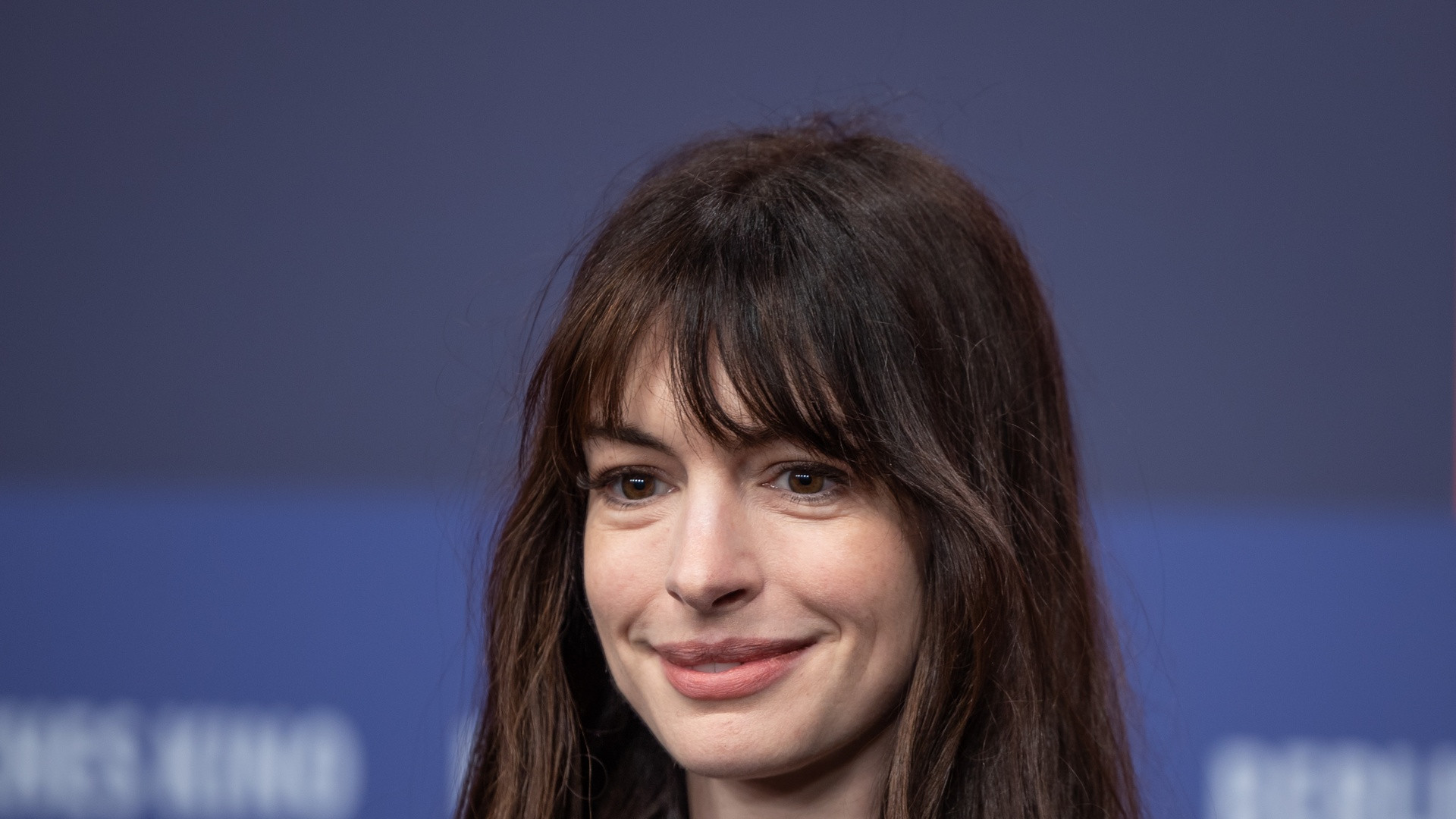 Portrait of Anne Hathaway in stylish white and silver attire looking thoughtfully ahead.