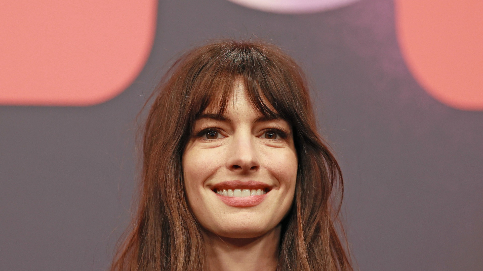 Radiant close-up photograph of Anne Hathaway at the 2023 Berlinale film festival with natural makeup and confident smile.