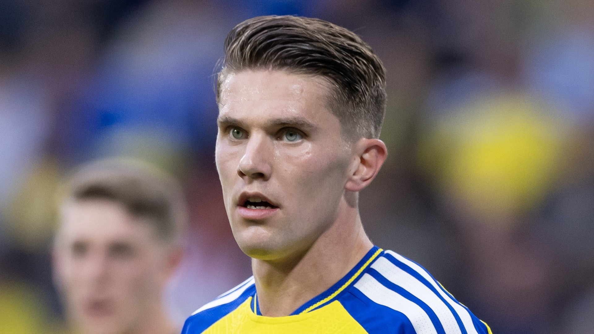 Close-up photograph of Viktor Gyökeres in blue and yellow kit with styled hair looking ahead intently.