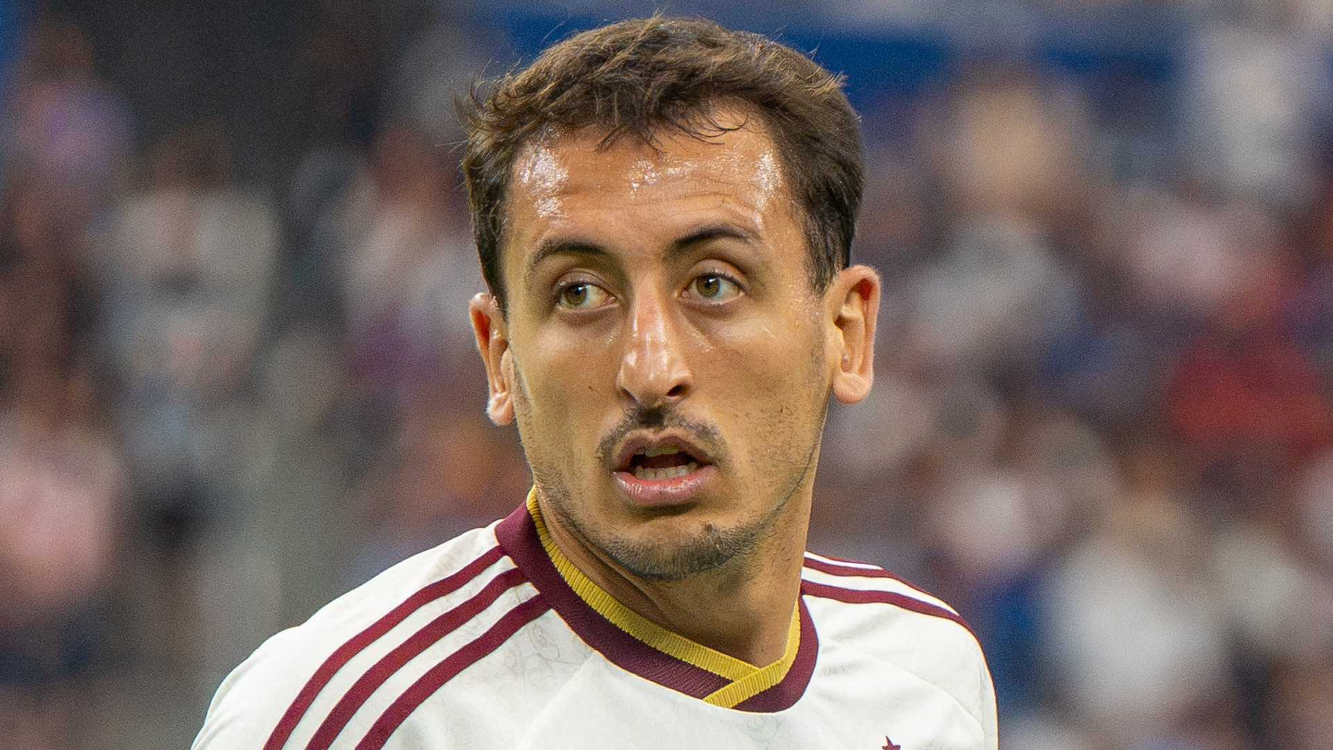 Close-up portrait of Mikel Oyarzabal in white and burgundy kit looking sideways during game action.