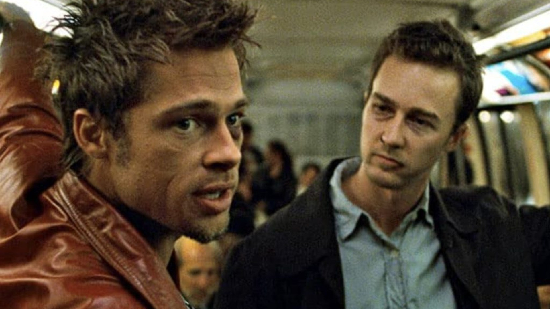 Tyler Durden in a red leather jacket speaking closely with the bruised narrator on a transit car, image horizontally flipped.
