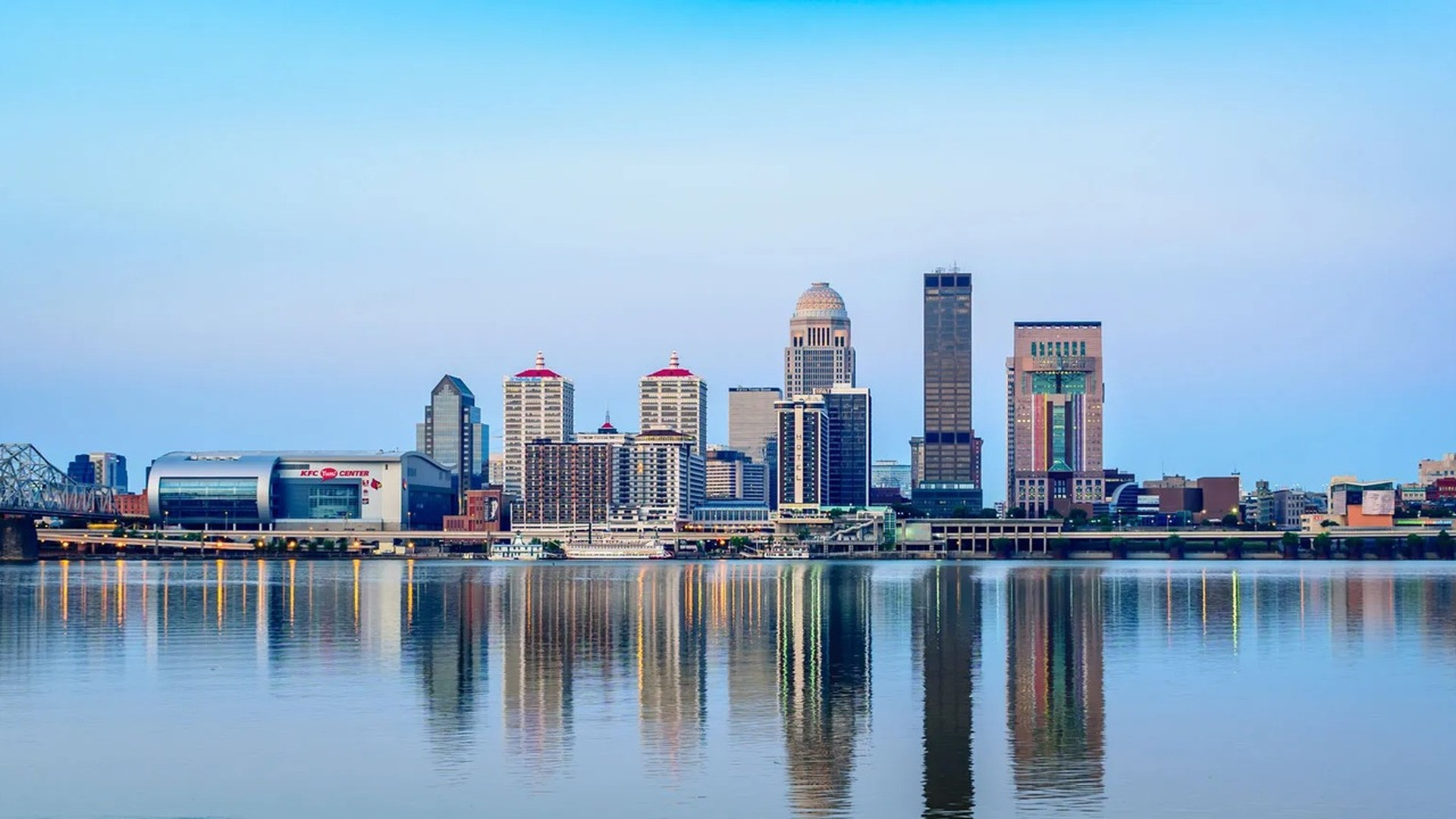 Louisville Kentucky skyline with modern high-rises and bridges stretching across the Ohio River.