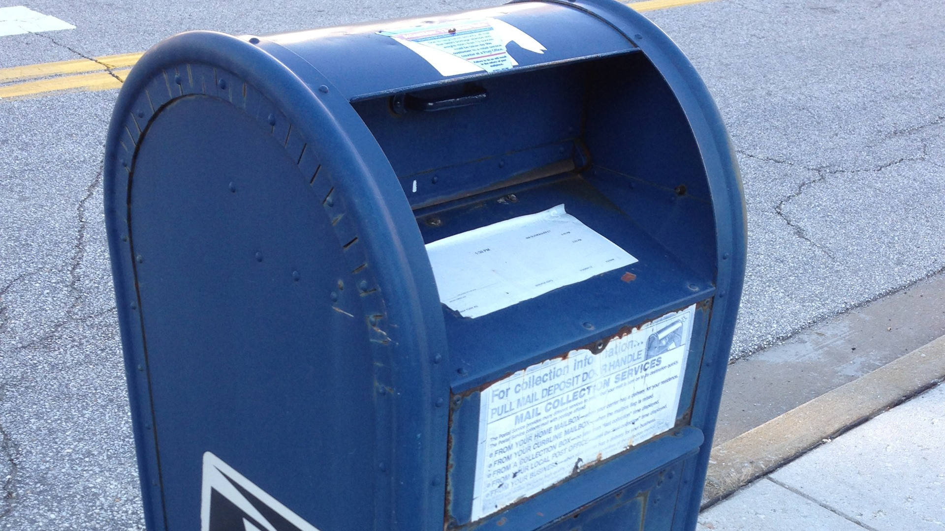 Official blue USPS collection mailbox on an American street.
