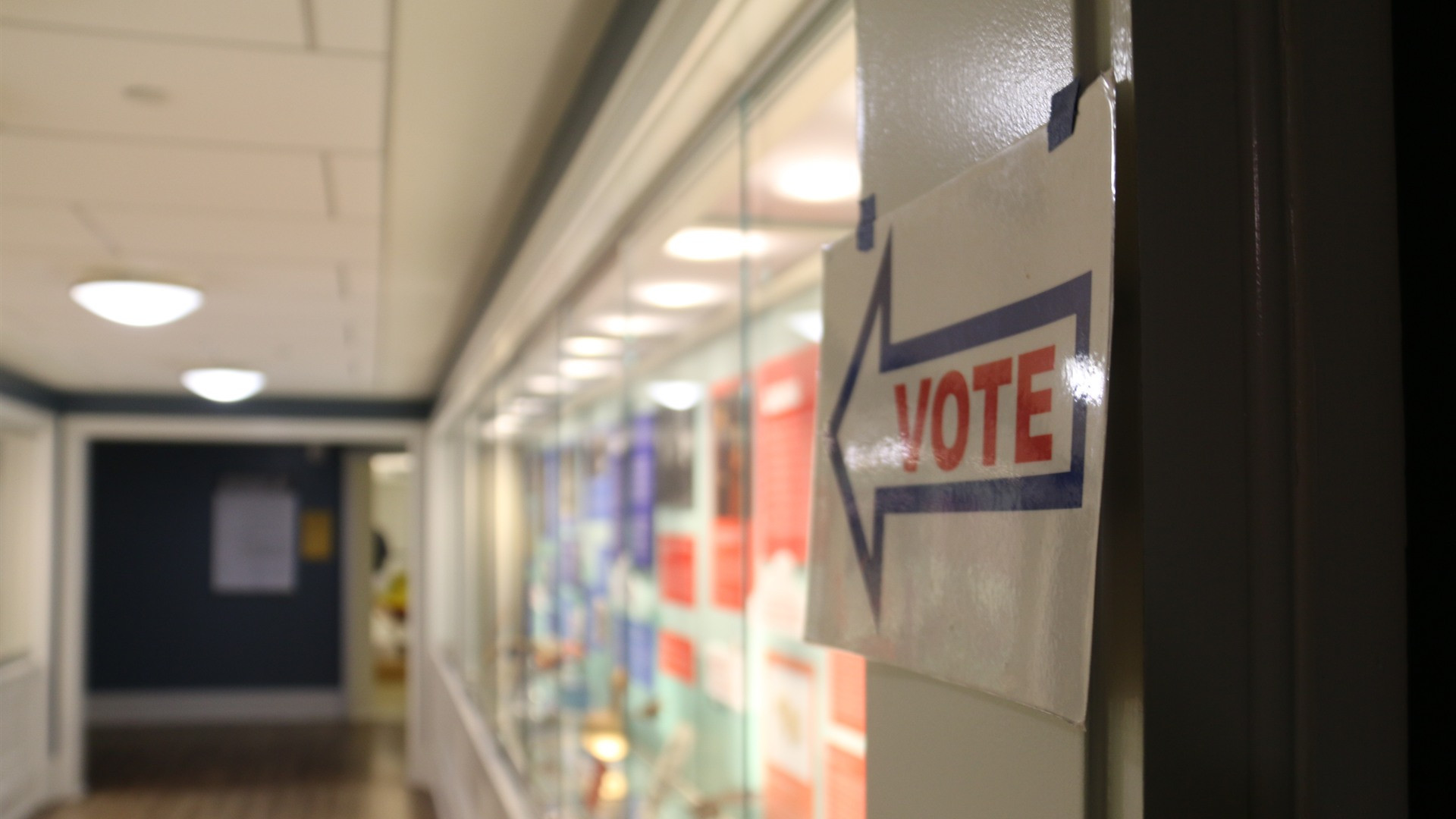 Modern election day polling precinct with voting booths and voters.